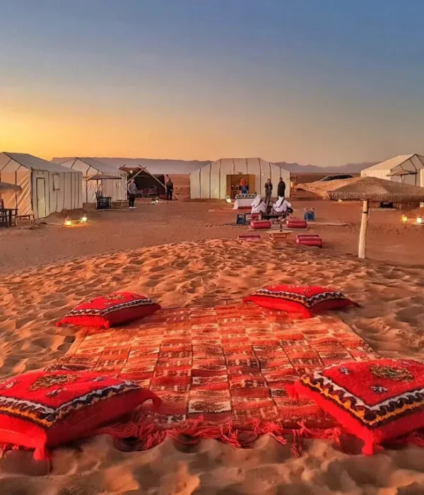 A serene desert scene featuring tents and colorful pillows arranged on the warm sand on our 2-Day Desert Tour from Marrakech to Zagora