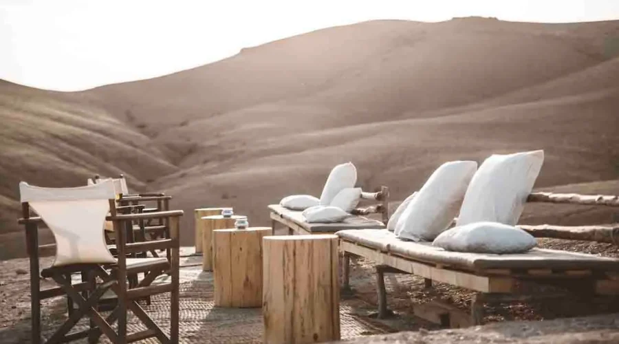 A wooden bench and chairs set against a vast desert landscape under a clear blue sky.