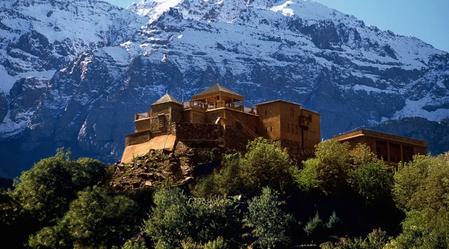 A building perched on a mountain, surrounded by majestic snow-capped peaks in the background.