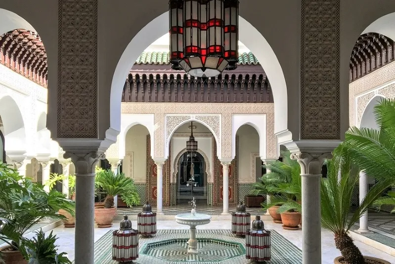 Hotel courtyard featuring a fountain surrounded by vibrant potted plants, ideal for relaxing during Morocco tours.