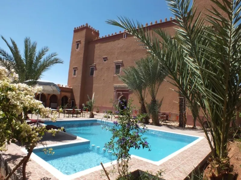 A large pool in front of an impressive building, showcasing a Morocco travel operator's luxurious destination.