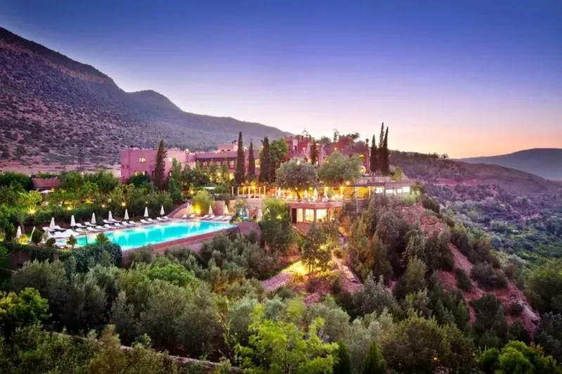 A hotel nestled among trees and mountains, showcasing the natural beauty of Morocco's landscape. 