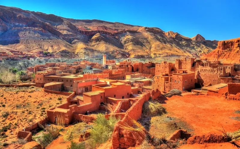A panoramic view of the village of Atlas nestled in the desert, showcasing its unique architecture and surrounding landscape.
