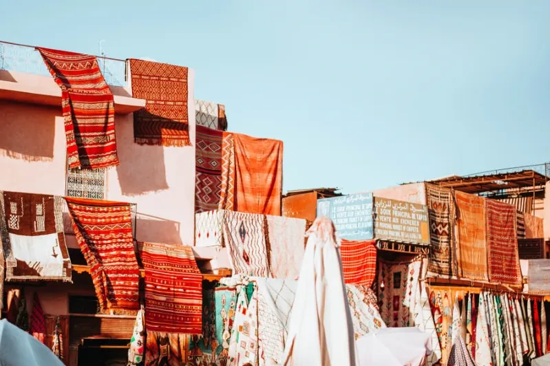  A vibrant market scene featuring colorful cloths hanging on the walls, best tour companies Morocco . 