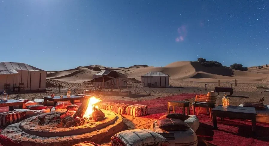 A desert fire pit illuminated by a full moon, creating a tranquil setting for Morocco Private Tours.
