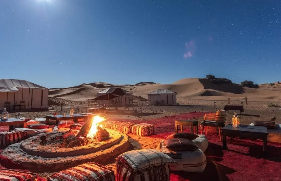 A desert fire pit illuminated by a full moon, creating a tranquil setting for Morocco Private Tours.