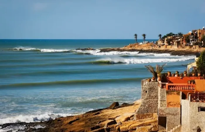 A scenic view of the beach and coastal houses in Morocco, ideal for surf travel enthusiasts.
