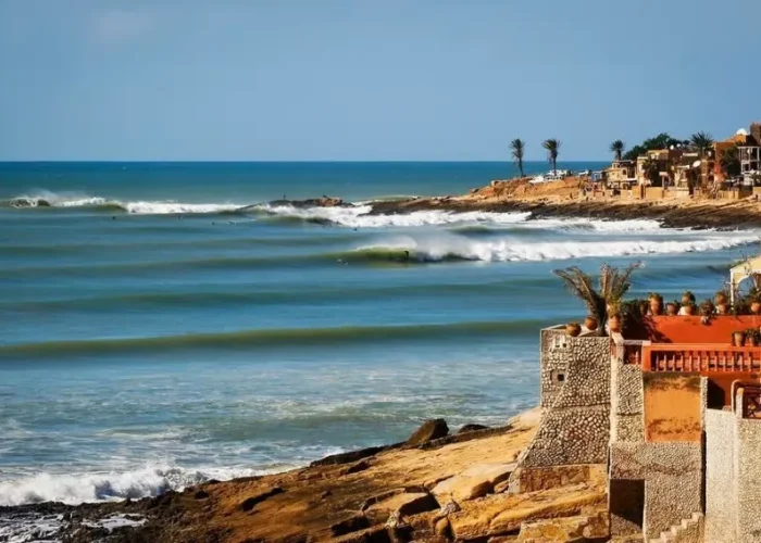 A scenic view of the beach and coastal houses in Morocco, ideal for surf travel enthusiasts.