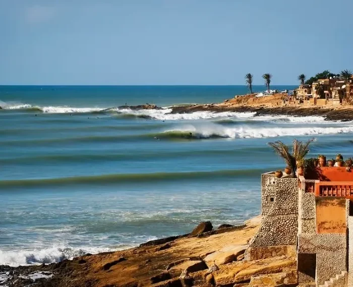 A scenic view of the beach and coastal houses in Morocco, ideal for surf travel enthusiasts.