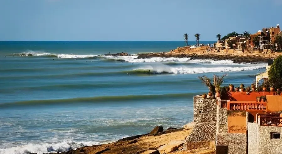 A scenic view of the beach and coastal houses in Morocco, ideal for surf travel enthusiasts.