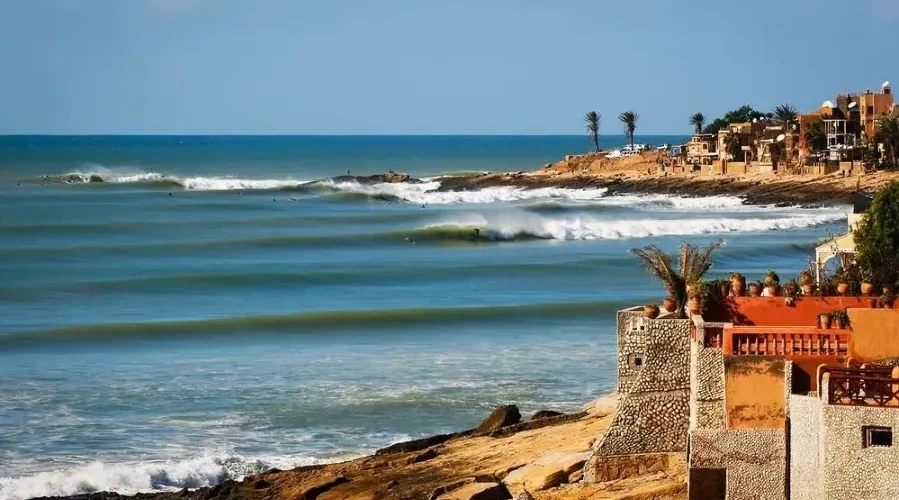 A scenic view of the beach and coastal houses in Morocco, ideal for surf travel enthusiasts.