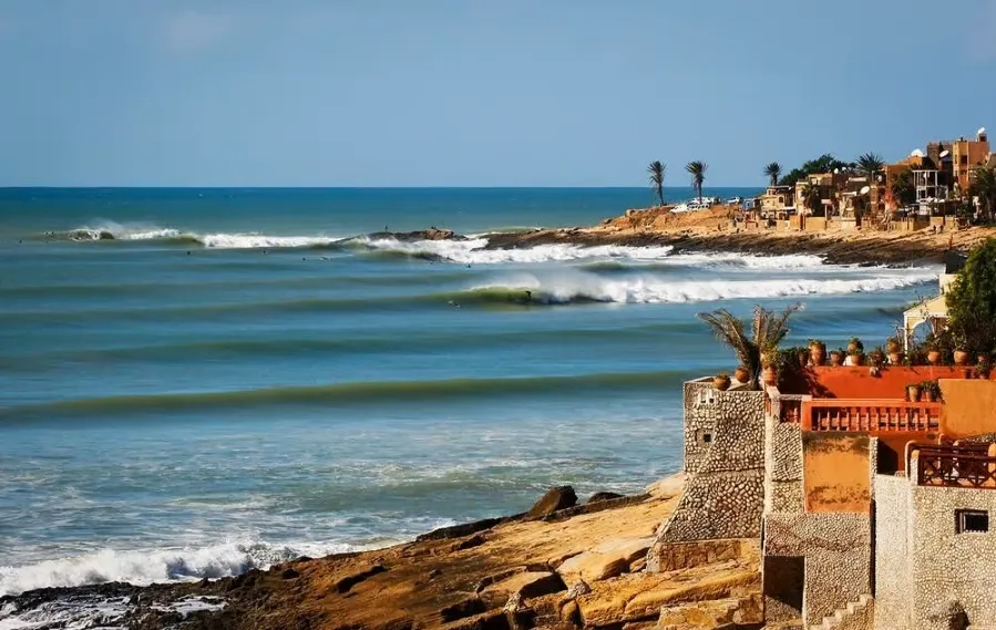 A scenic view of the beach and coastal houses in Morocco, ideal for surf travel enthusiasts.