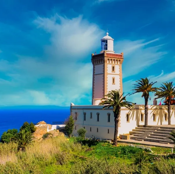 A lighthouse perched on a hill, overlooking the ocean, symbolizing coastal beauty in Morocco.