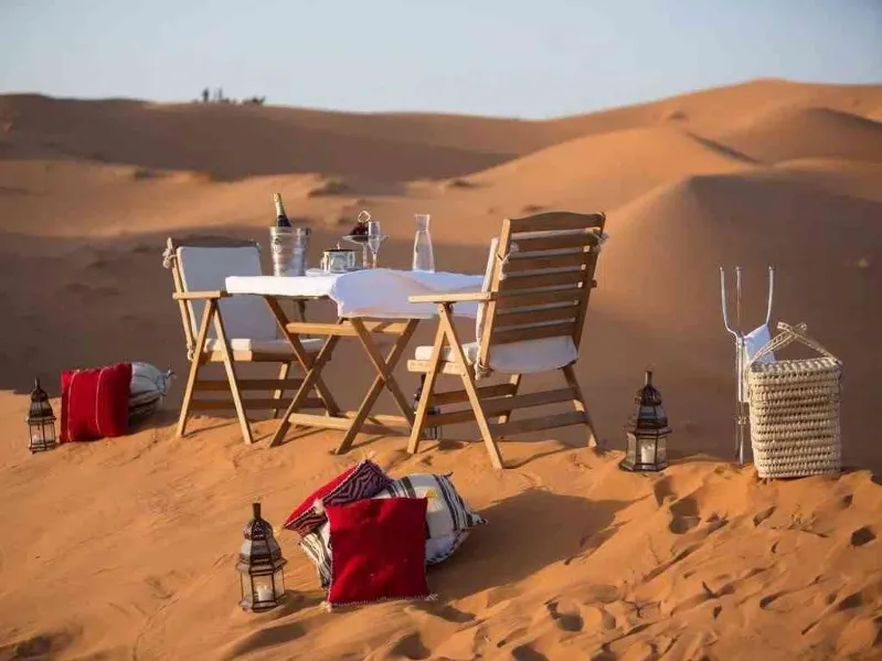 A beautifully set dinner table in the desert, showcasing a unique dining experience during a 3-day tour from Marrakech.