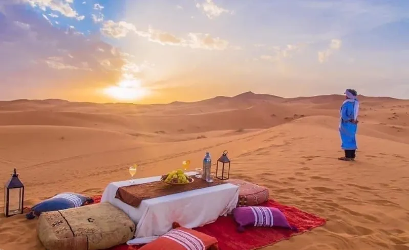 A romantic dinner set against a vibrant Sahara Desert sunset, showcasing the beauty of Morocco's landscapes.