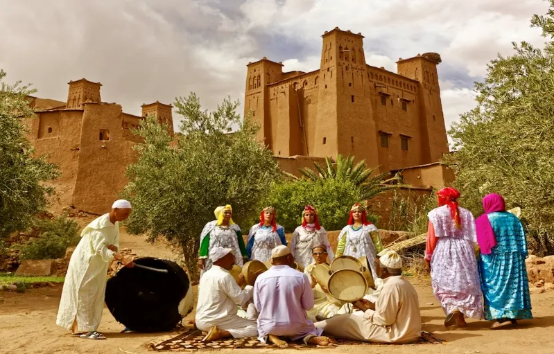 A group of people in traditional Moroccan clothing playing drums, showcasing cultural music during a tour event.