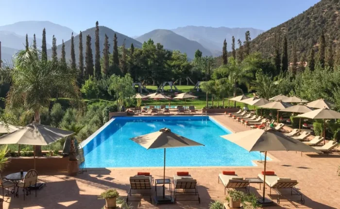 A luxurious pool area in Morocco, featuring lounge chairs and umbrellas for relaxation under the sun.