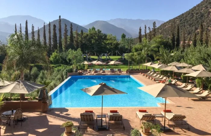 A luxurious pool area in Morocco, featuring lounge chairs and umbrellas for relaxation under the sun.