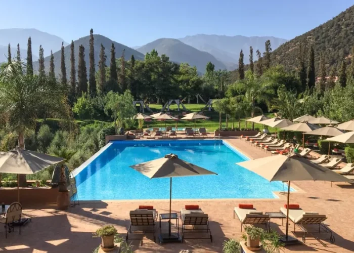 A luxurious pool area in Morocco, featuring lounge chairs and umbrellas for relaxation under the sun.
