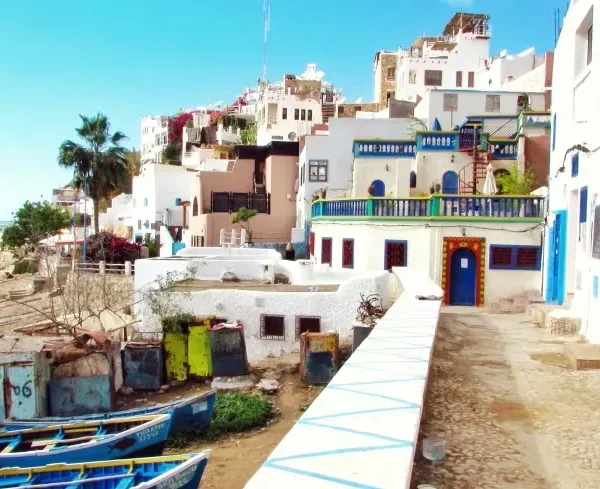A scenic beach view with blue boats in the background, featured in a Morocco vacation travel guide.
