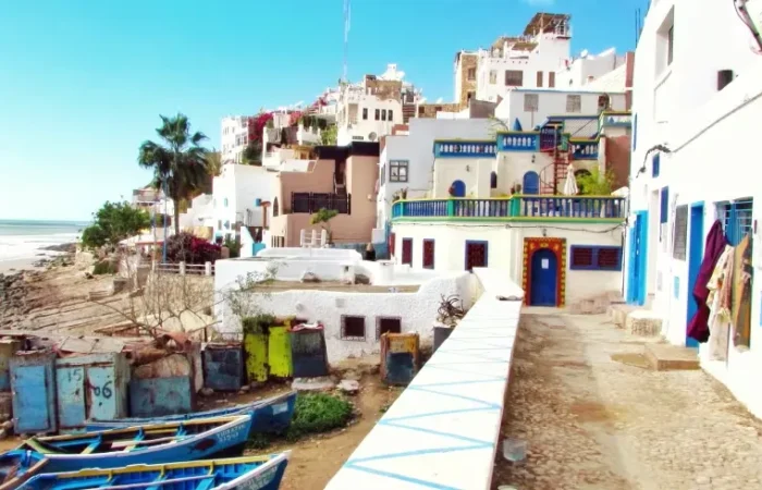 A scenic beach view with blue boats in the background, featured in a Morocco vacation travel guide.