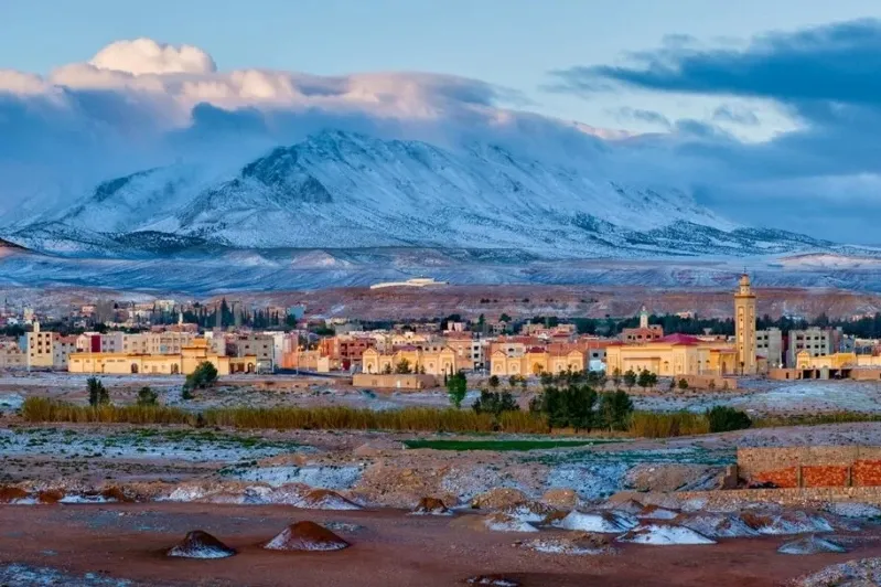 Snow-covered mountains loom over the distant city of Morocco, highlighting its beauty, especially in the best visiting month.