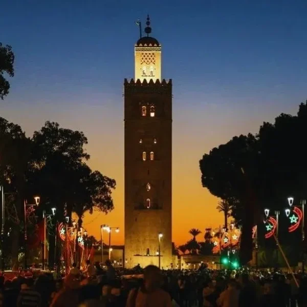 Sunset view of the clock tower in Marrakech, highlighting its silhouette against a vibrant sky for a travel guide.
