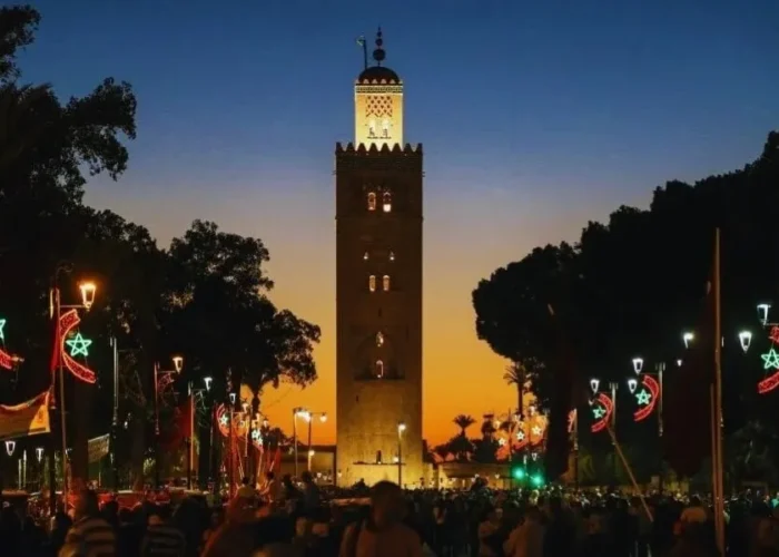 Sunset view of the clock tower in Marrakech, highlighting its silhouette against a vibrant sky for a travel guide.