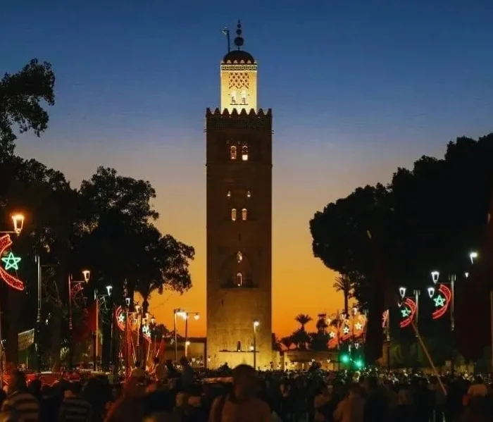 Sunset view of the clock tower in Marrakech, highlighting its silhouette against a vibrant sky for a travel guide.