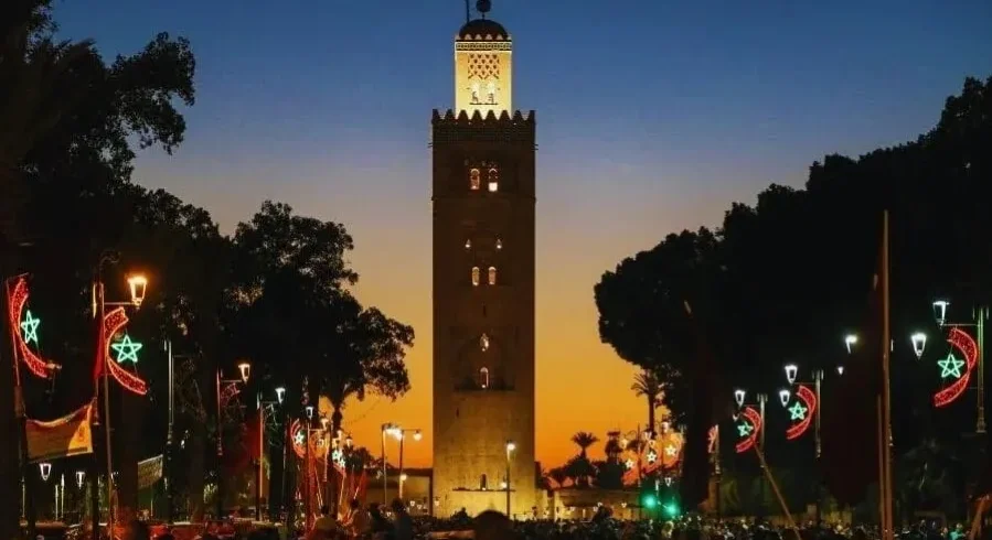 Sunset view of the clock tower in Marrakech, highlighting its silhouette against a vibrant sky for a travel guide.