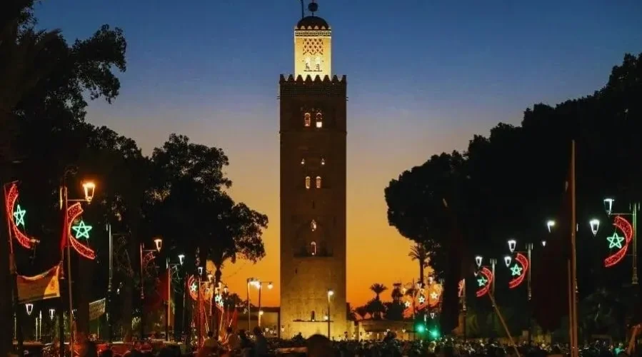 Sunset view of the clock tower in Marrakech, highlighting its silhouette against a vibrant sky for a travel guide.