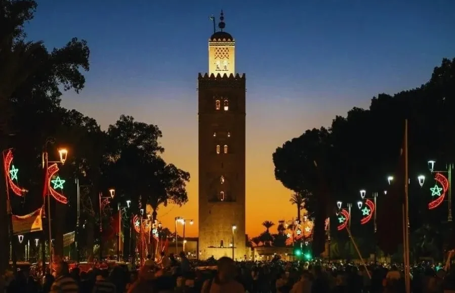 Sunset view of the clock tower in Marrakech, highlighting its silhouette against a vibrant sky for a travel guide.