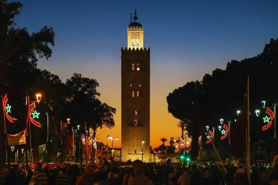 Sunset view of the clock tower in Marrakech, highlighting its silhouette against a vibrant sky for a travel guide.