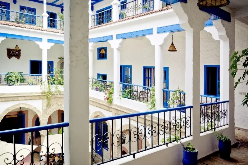 A vibrant courtyard featuring blue and white walls with decorative balconies, showcasing Marrakech's unique architectural style.