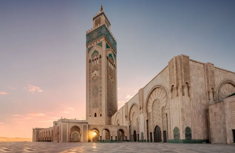 A stunning sunrise casts light on the mosque in Casablanca, showcasing its grandeur as a must-see attraction.things to see in Casablanca