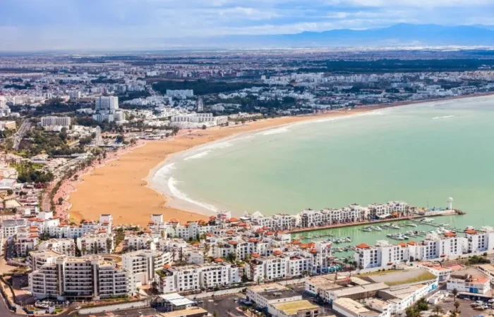 Aerial view of Marrakech, Morocco, showcasing its vibrant architecture and layout, with a suggestion to visit Agadir.
