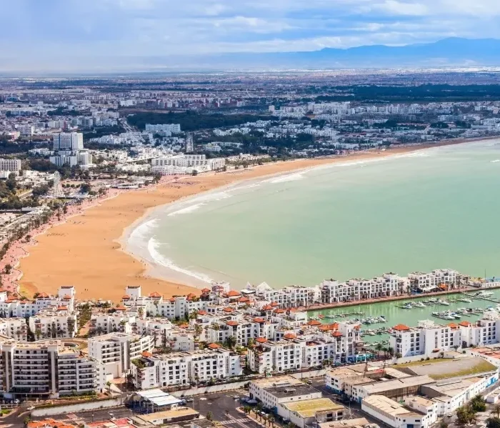 Aerial view of Marrakech, Morocco, showcasing its vibrant architecture and layout, with a suggestion to visit Agadir.