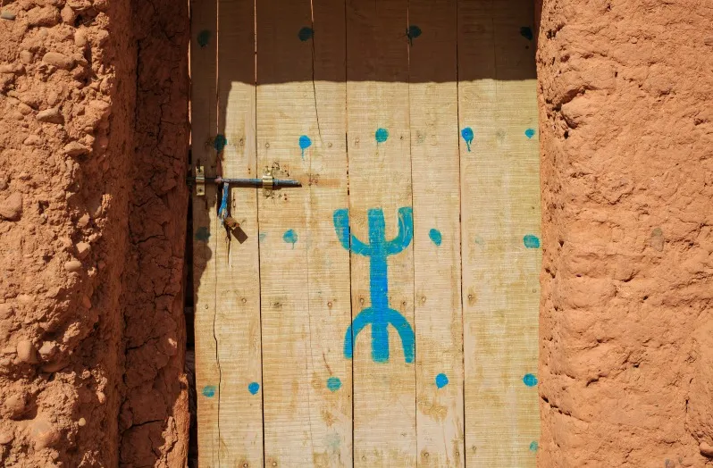A wooden door featuring a blue symbol, representing Moroccan culture, inviting visitors to explore cultural tours.