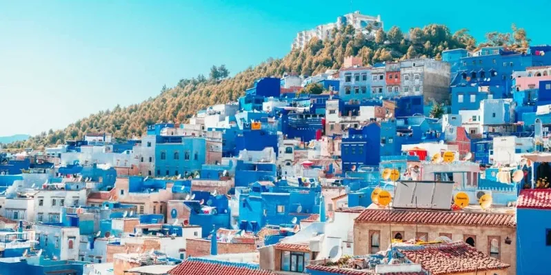 A panoramic view of Chefchaouen, Morocco, showcasing its iconic blue buildings and vibrant streets, promoted by a Morocco tours agency.