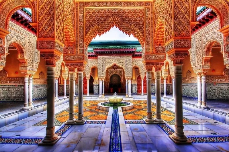 The serene courtyard of the Alhambra Palace in Morocco, showcasing intricate architecture and lush greenery.