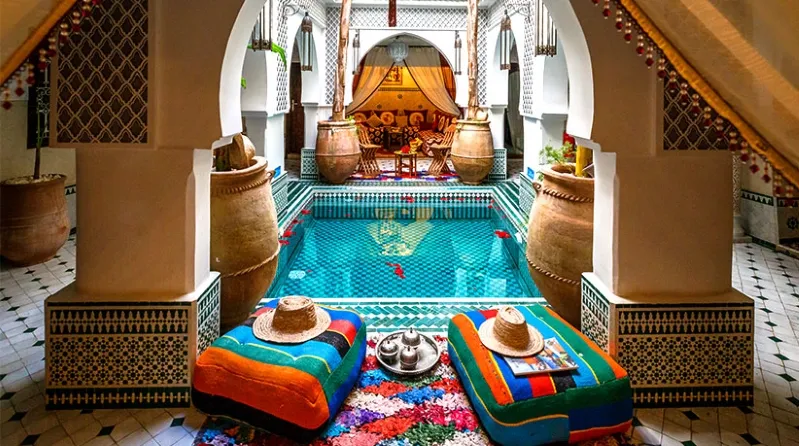 A luxurious pool area featuring colorful pillows and a large rug, ideal for relaxation during Morocco luxury tours.