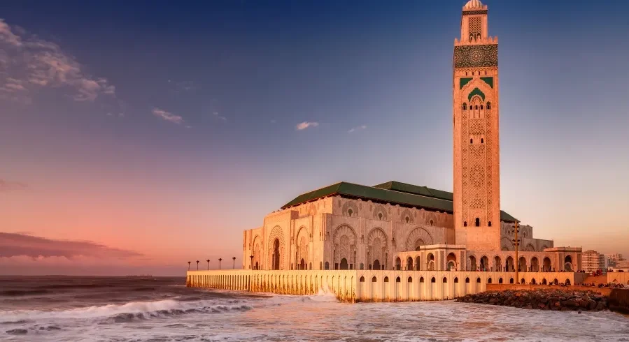 The Hassan II Mosque in Casablanca, Morocco, illuminated by sunset, showcasing its stunning architecture during a guided tour.