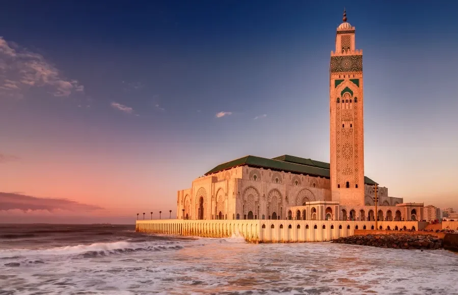 The Hassan II Mosque in Casablanca, Morocco, illuminated by sunset, showcasing its stunning architecture during a guided tour.