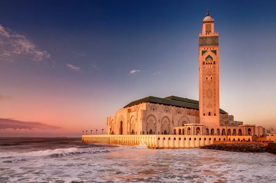 The Hassan II Mosque in Casablanca, Morocco, illuminated by sunset, showcasing its stunning architecture during a guided tour.