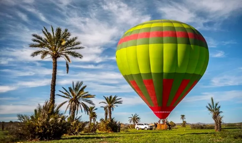 A colorful hot air balloon soars over a lush green field in Morocco, capturing the essence of a scenic balloon ride.