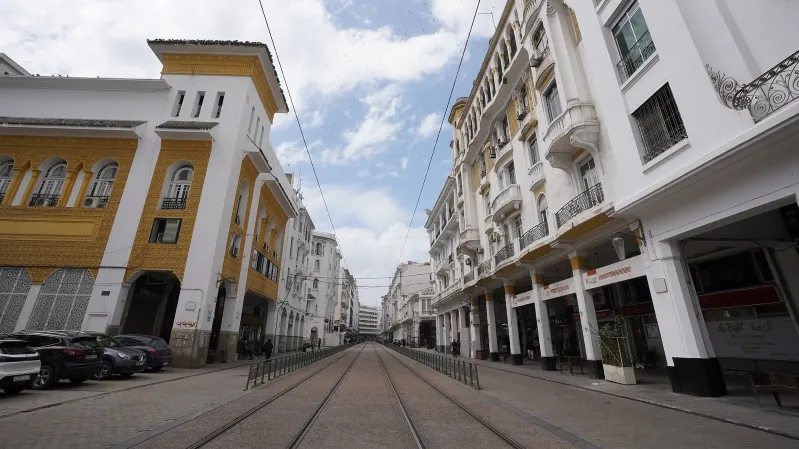 A street in Casablanca featuring a train track alongside parked cars, showcasing urban life and transportation.