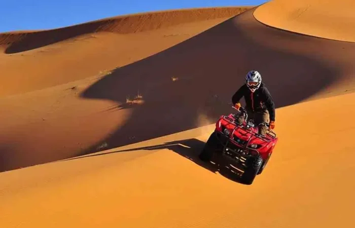 A man riding an ATV through the desert during the Marrakech to Fes Desert Tour, with sand dunes in the background.