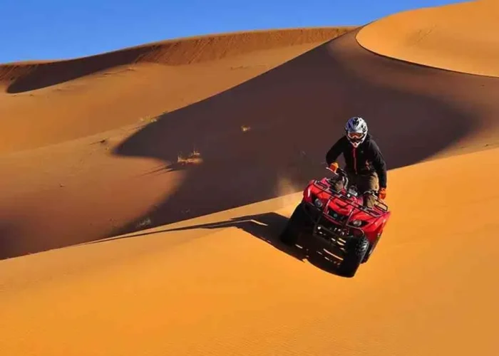 A man riding an ATV through the desert during the Marrakech to Fes Desert Tour, with sand dunes in the background.