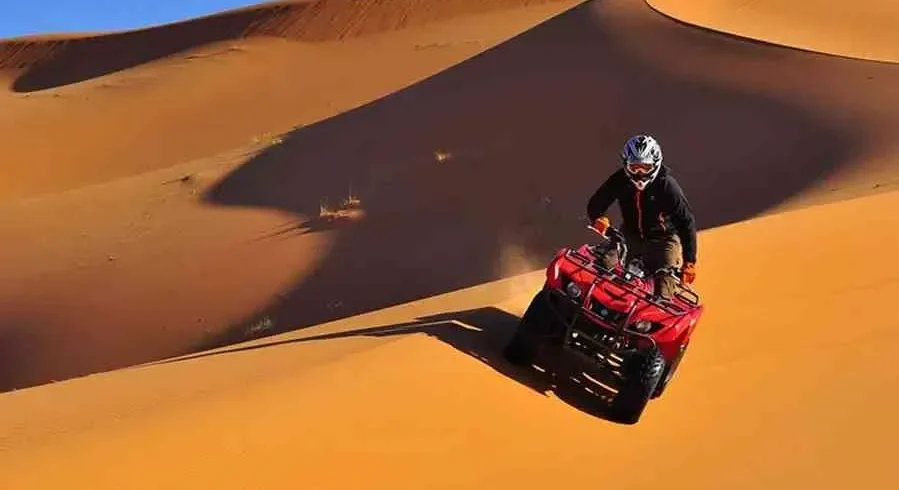 A man riding an ATV through the desert during the Marrakech to Fes Desert Tour, with sand dunes in the background.