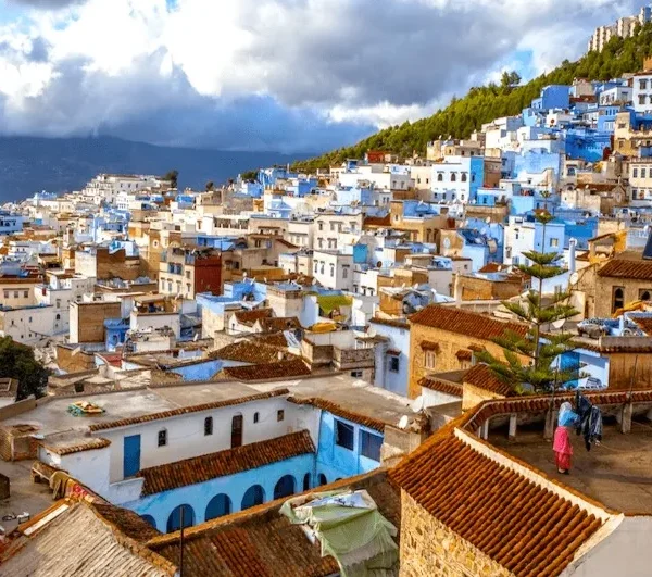 Scenic view of Chefchaouen, Morocco, showcasing its iconic blue buildings and mountainous backdrop under a clear sky.